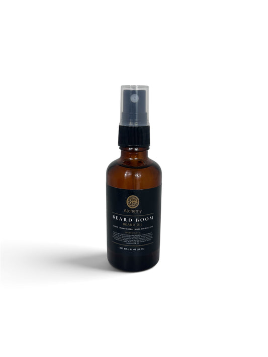 An amber glass bottle spray bottle with a black spray top and a black label of Alchemy Body Werks Beard Boom Beard Oil on a soft white background.