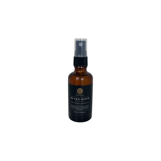 An amber glass bottle spray bottle with a black spray top and a black label of Alchemy Body Werks Beard Boom Beard Oil on a white background.