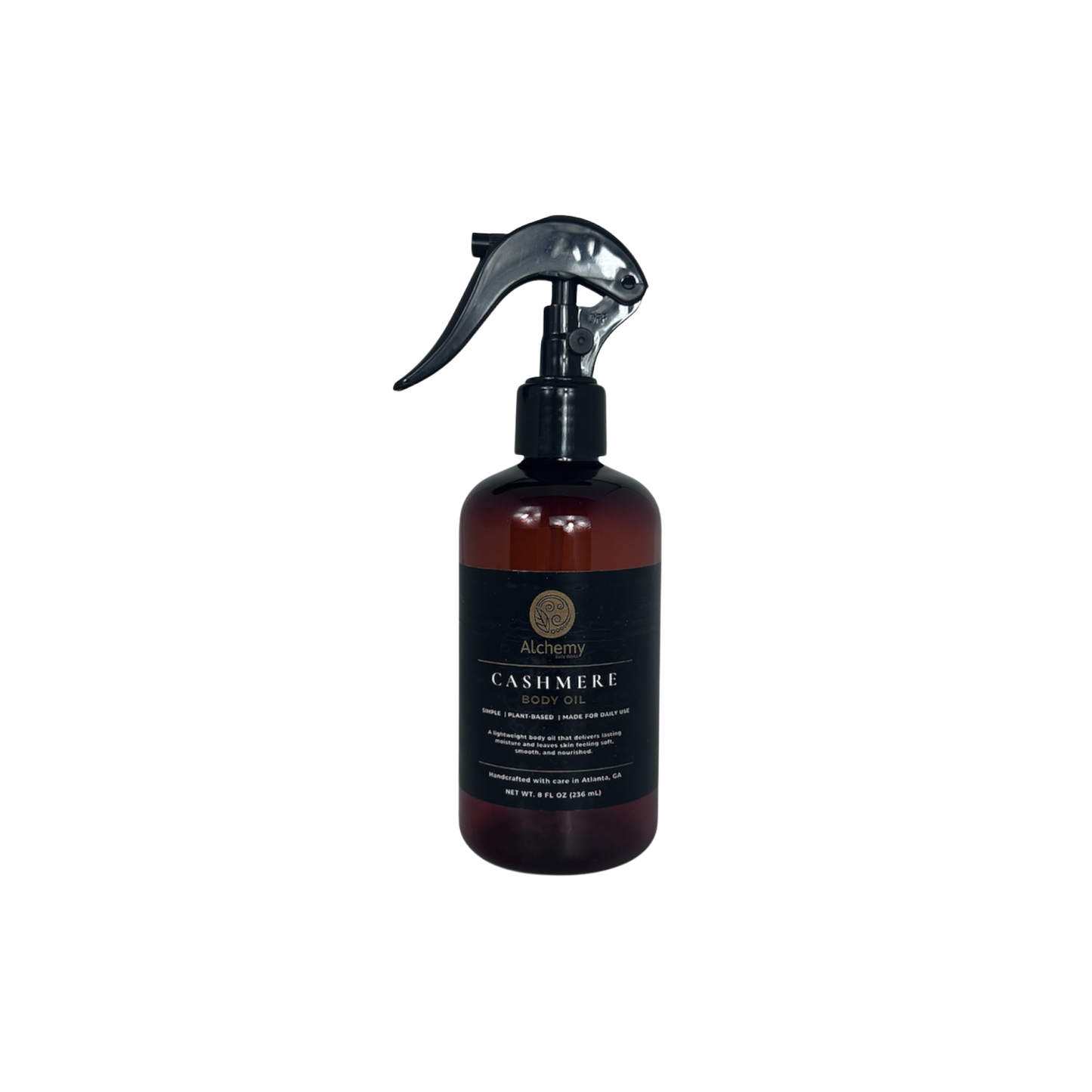 An amber spray bottle with a black trigger sprayer and a black label of Alchemy Body Werks Cashmere Body Oil on a clean white background.