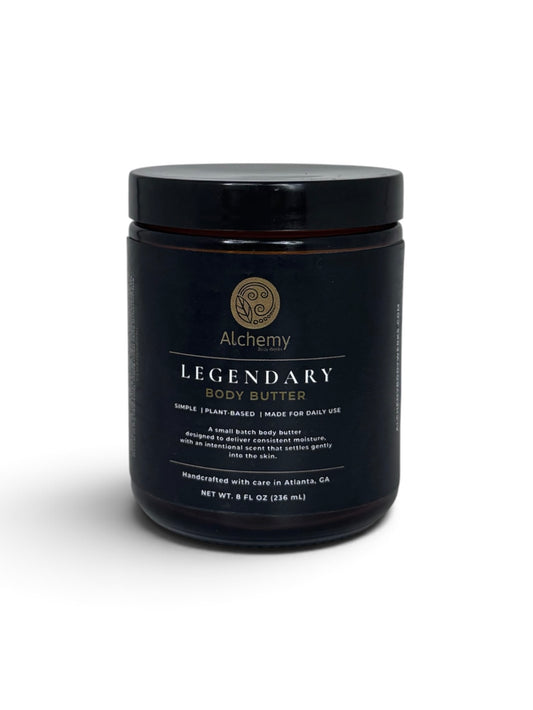 An amber jar with black lid and black label of Alchemy Body Werks Legendary Body Butter on a white background with a soft shadow.