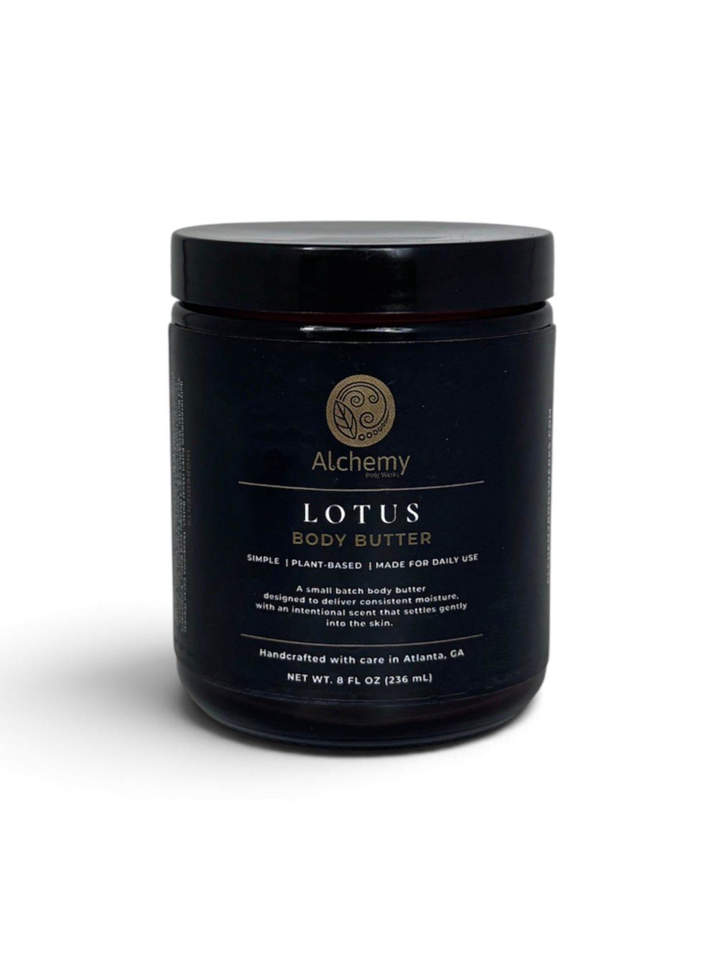 An amber jar with black lid and black label of Alchemy Body Werks Lotus Body Butter on a white background with a soft shadow.